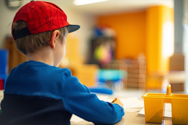 Young child learning to write at desk (4–5 years)